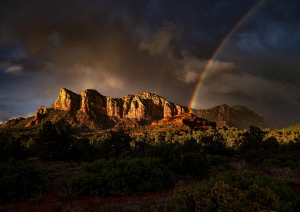 пейзаж с горами, покрытыми лесом, и радугой на фоне облачного неба